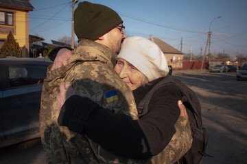 Military son hugs an elderly mother goodbye. Mom hugs a Ukrainian soldier. militarization. The...