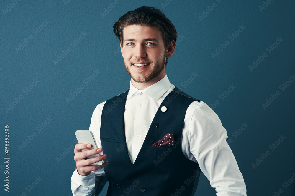 Poster Staying in touch via text. Studio shot of a handsome young businessman sending a text message against a blue background.