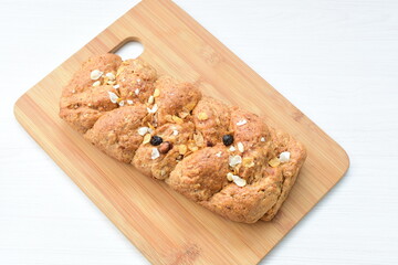 Healthy wholemeal big bread, with cereals, raisins, peanuts and honey on white wooden background