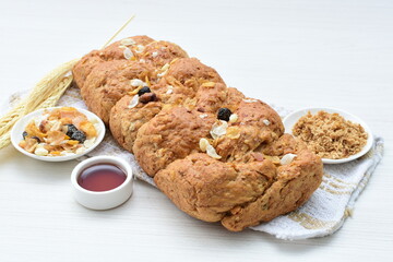 Healthy wholemeal big bread, with cereals, raisins, peanuts and honey on white wooden background