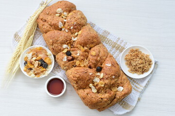 Healthy wholemeal big bread, with cereals, raisins, peanuts and honey on white wooden background