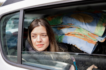 Getting a university in a city different from the city you live in. College young girl is going to another city to study. Her family takes her to that city. Back of car is full of stuff. She is sad.