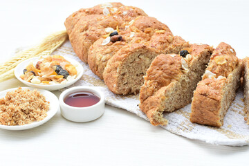 Healthy wholemeal big bread, with cereals, raisins, peanuts and honey on white wooden background