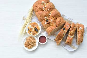 Healthy wholemeal big bread, with cereals, raisins, peanuts and honey on white wooden background