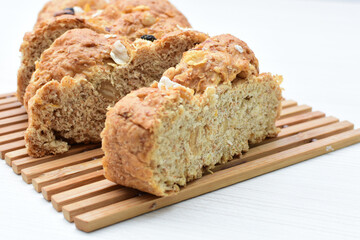 Healthy wholemeal big bread, with cereals, raisins, peanuts and honey on white wooden background