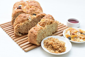 Healthy wholemeal big bread, with cereals, raisins, peanuts and honey on white wooden background