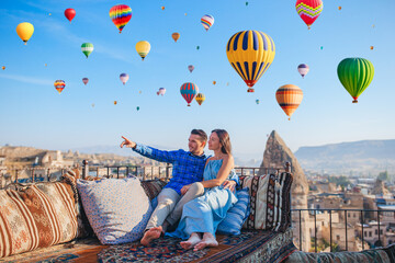 Happy young couple during sunrise watching hot air balloons in Cappadocia, Turkey - 496395161