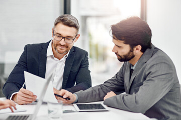 Let me take a look at that.... Cropped shot of two businessmen going over some paperwork in their...