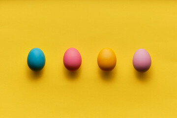 four colorful easter eggs in a row on yellow paper with plenty of copy space