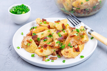 Bacon and onion potato salad dressed with apple cider vinegar and mustard, on plate, horizontal
