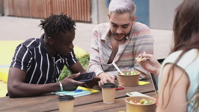 Diverse friends eating take away food outdoor - Real people millennial lifestyle