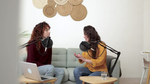 Female host recording radio podcast interview with guest at home office
