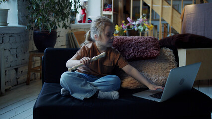 A child opens a laptop and searches the Internet for a video lesson of playing the flute