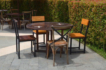 Fototapeta na wymiar Empty Cafe Chairs And Tables In The Garden On Sunny Day