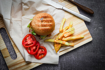 Beef burgers served on paper With french fries and tomatoes, it's a popular food.