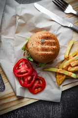Beef burgers served on paper With french fries and tomatoes, it's a popular food.
