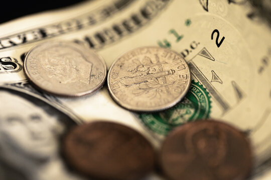 Nota de 1 Dólar dos Estados Unidos com moedas em fotografia macro. Conceitos de economia e finanças. Foco na moeda de dez centavos de dólar.
