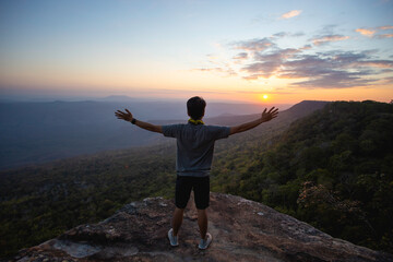 man raises his hands to heaven as a sign of freedom or victory and in the background a fantastic landscape. Concept of: breathing, freedom, journey, life, love..