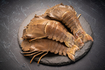 Fresh Flathead lobster on black plate, Raw Flathead lobster or Mantis shrimp on black plate on...