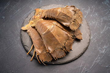 Fresh Flathead lobster on black plate, Raw Flathead lobster or Mantis shrimp on black plate on black background,