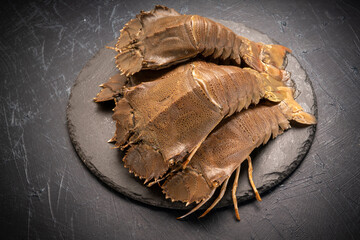 Fresh Flathead lobster on black plate, Raw Flathead lobster or Mantis shrimp on black plate on black background,