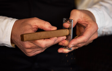 Ending the day on a good note. Shot of an unrecognizable man using a clipper to cut a cigar.
