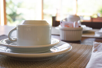 Mesa de Café da manhã com xícara de café ou de chá com um ambiente emadeirado e com verdes