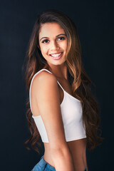 Boost your self confidence with a smile. Studio portrait of an attractive young woman posing against a dark background.