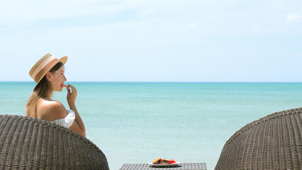 Happy young woman on tropical sea vacation at luxury hotel resort. Female tourist in straw hat...