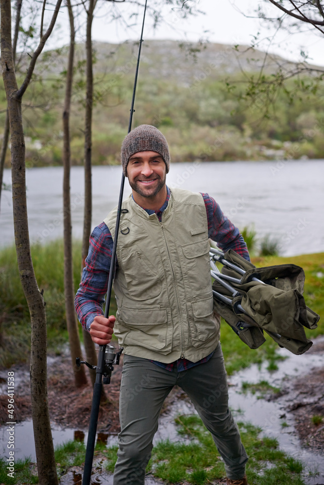 Wall mural Fishing - his idea of fun. Portrait of a handsome young man enjoying his fishing trip.