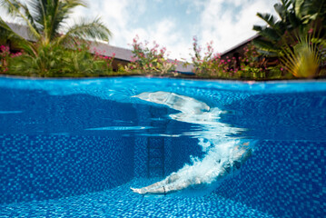 Fototapeta na wymiar A view of a person dives into the pristine blue swimming pool at daytime.