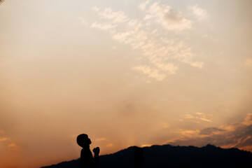 Silhouette of a man prayer on mountain at sunset. concept of religion.