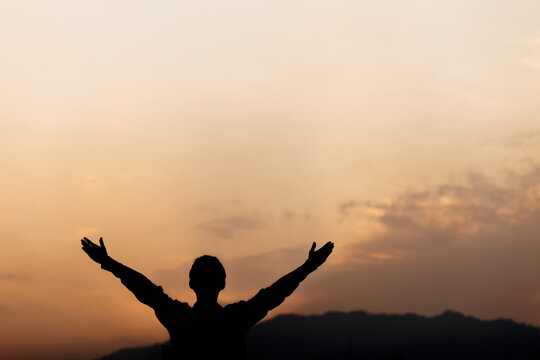 Silhouette of a man lift hands up and prayer at sunset. concept of religion.