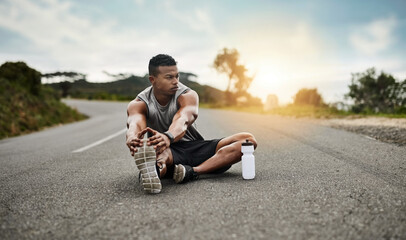 The proper warmup makes all the difference. Shot of a sporty young man stretching his legs while exercising outdoors.