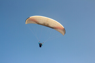Paraglider flying along in the sky , paraglide flying gliding on a clear blue sky, white paragliding