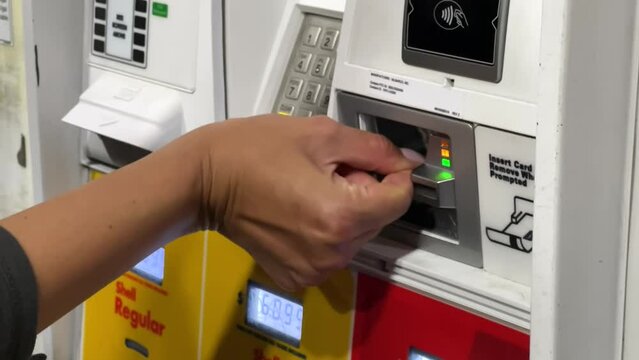 Using a credit card at the pump at a gas station as prices soar - woman's hand paying for gas
