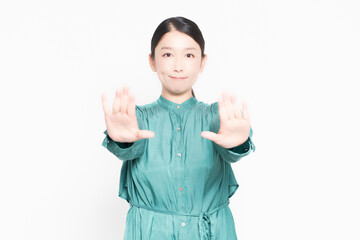 白い背景の前に立ってNGのジェスチャーをする主婦