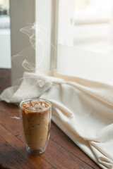 Ice coffee on table with cream being poured into it showing the texture and refreshing look of the drink