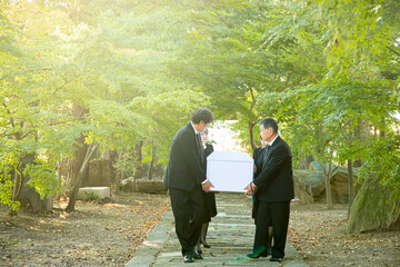 お葬式で棺桶を運ぶ遺族
