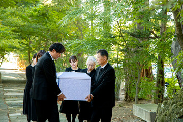 お葬式で棺桶を運ぶ遺族
