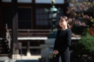 葬儀に来た喪服の若い女性（寺院）
