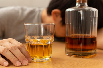 Alcohol addicted man sleeping at the table. Sad depressed male adult having troubles with alcohol.