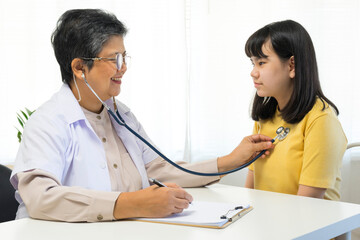 Asian woman pediatrician doctor hold stethoscope for exam a little girl patient, Good family doctor visiting child at home, Healthcare and medicine for childhood concept.