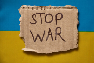 Cardboard plate with the inscription stop war against the background of the flag of Ukraine, yellow-blue