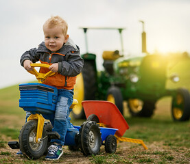 Nothing beats having a farm for playground. Portrait of an adorable little boy riding a toy truck on a farm.