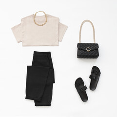 Beige t-shirt, black pants, bag with chain strap, flat sandals, gold chain necklace on white background. Woman's casual outfit. Trendy stylish basic minimalistic look. Women clothes, flat lay.