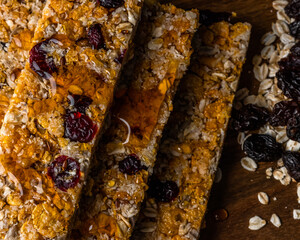 cereal bars on table with honey, oatmeal, red cranberries, raisins