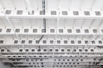 White painted steel ceiling on the vessel with stiffeners, piping and electrical wiring on the ceiling.