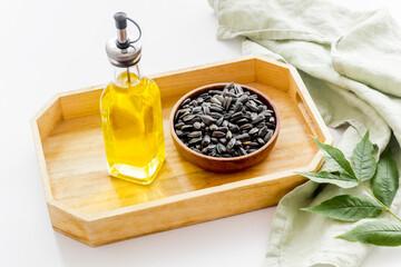 Bottle of sunflower cooking oil with seeds in bowl