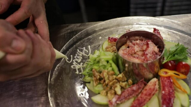 Gastronomy. Seafood. Male chef decorating with a piping bag, a fresh Spider Crab dish in the restaurant kitchen. 